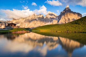 The Pale di San Martino peaks (Italian Dolomites) reflected in the water at sunset, with an alpine...