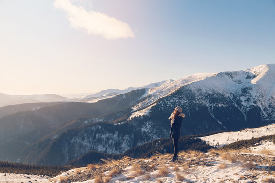 Winter view of a young woman admiring mountain landscape. Selective focus. Film filter
