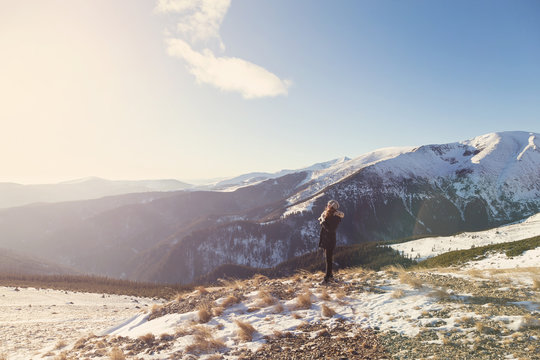 Winter view of a young woman admiring mountain landscape. Selective focus. Film filter