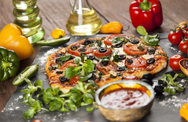 Tasty pizza, tomatoes and others ingredients on a wooden backgro