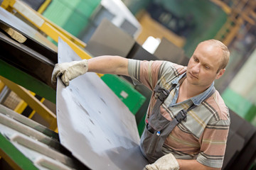 Fototapeta na wymiar Factory Man Worker Moving Metal Sheet in Workshop during Manufacturing Process