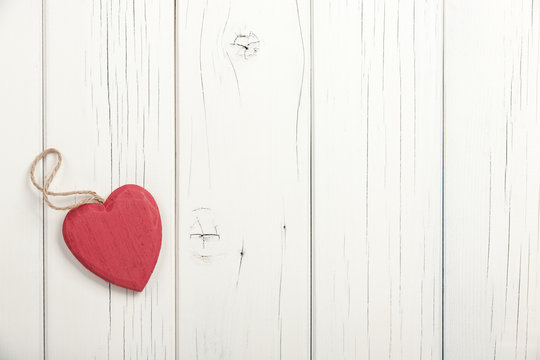 Red wooden heart on white wooden background