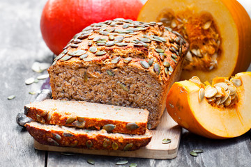 Sliced  pumpkin bread loaf on wooden cutting board with seeds