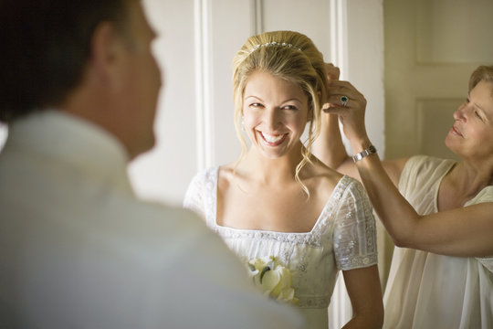 A bride has her hair pinned up by her mother