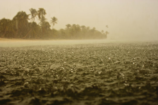 Hard rain splashing on the surface of the sea near a tropical island.