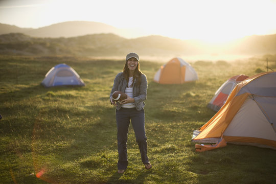 Young Woman Throwing A Football In A Campsite At Sunset