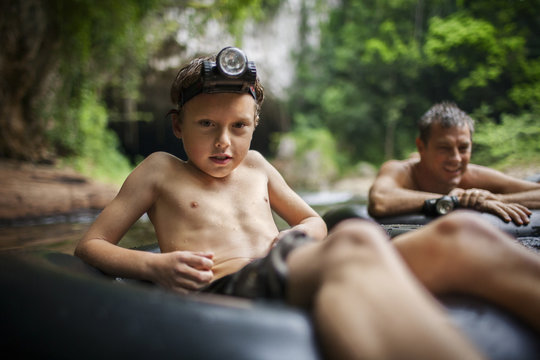 Boy and his father sitting in inflatable rings  in river