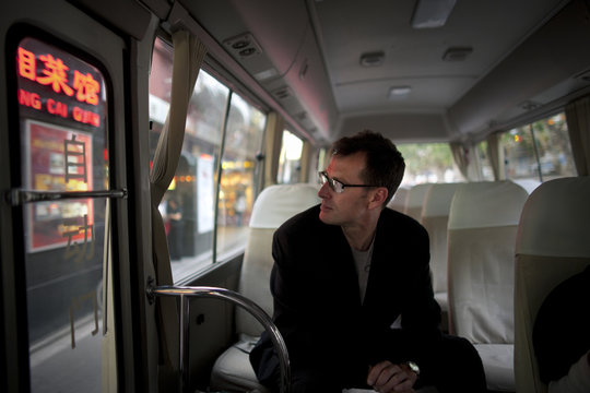 Mid-adult man sitting alone inside a small bus.