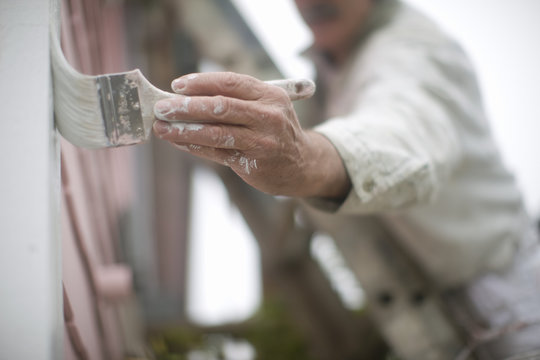 Man Painting The Exterior Of A House