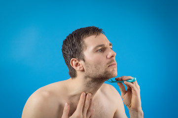 a guy has a shave, blue background