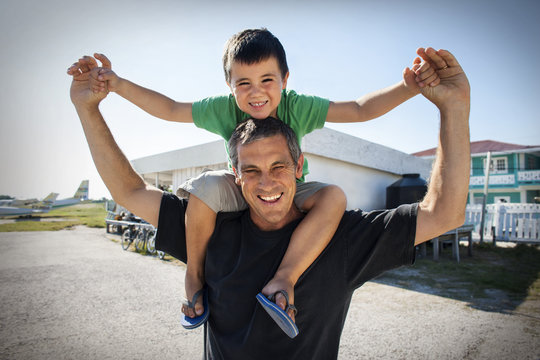Portrait of a smiling father holding his son on his shoulders.