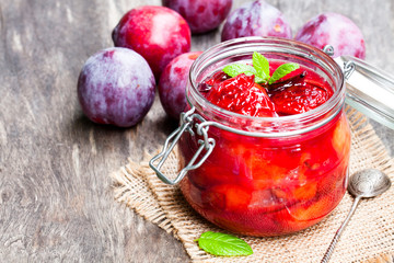 Baked  plums with caramel and vanilla pod in a clear glass jar