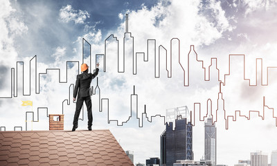 Man architect draw silhouette of modern city on blue sky. Mixed 