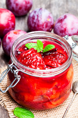 Baked  plums with caramel and vanilla pod in a clear glass jar