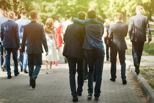 stylish confident man in suit having fun, group of people walkin