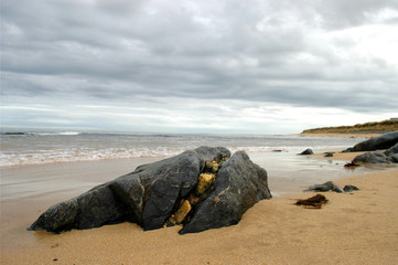 Split boulder on beach with smaller rocks filling up the crack