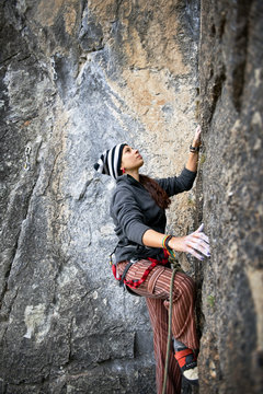 Woman reaching for the next hand hold while rock climbing.