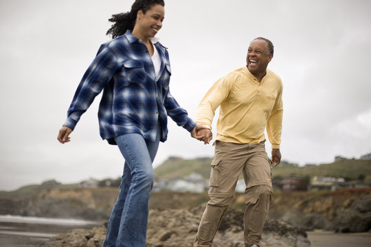 Mature man and woman holding hands at the beach