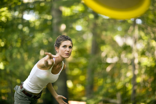 Woman throwing a frisbee in a forest.