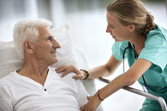 Portrait of a senior man in a hospital bed,  and a young female doctor.