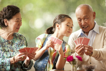 Senior couple playing cards with their granddaughter.