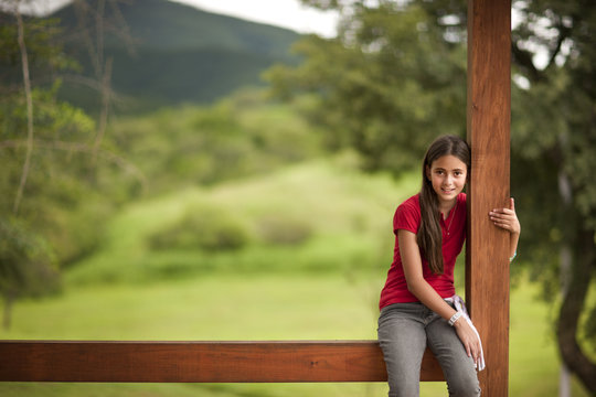 Portrait of young girl sitting on verandah in a rural setting.