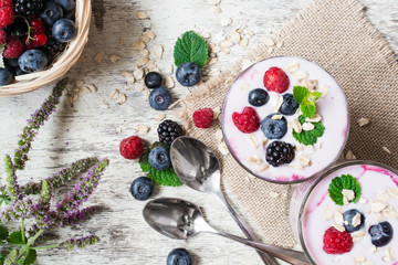 healthy yogurt with berries, oats and mint in two glasses
