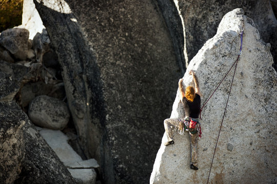 Woman climbing large rock-face.