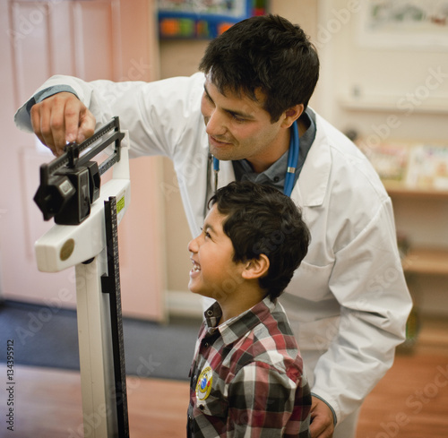 "Doctor measuring young patient's weight on medical scales." Stock ...