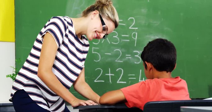 Teacher helping schoolboy with their studies in classroom at school 4k