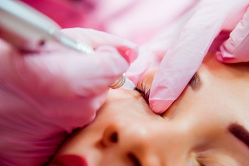 Obraz na płótnie Canvas Close up Permanent make up (tattoo). Medical Cosmetologist applying permanent makeup on eyes. Selective focus