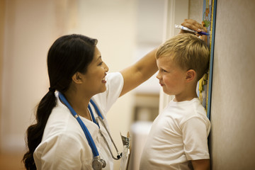 Little boy having his height measured by the nurse.
