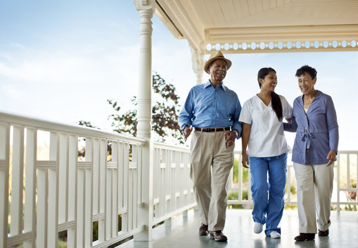 Nurse walking with senior couple on deck of rest-home.