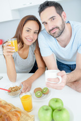 Obraz na płótnie Canvas young happy couple having breakfast together with fruits and juice