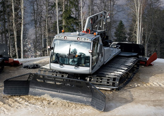 A snow tracktor with a small crane parked