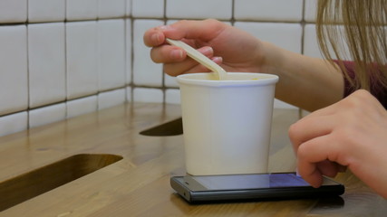 Woman eating soup and using smartphone in cafe. Technology and fast food concept
