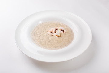 Cream soup with mushrooms on a white plate
