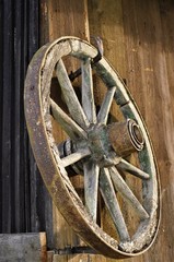 Obraz premium the wheel of an old car hanging from the old barn