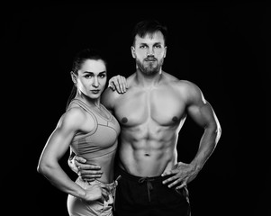 Fototapeta na wymiar Young sporty couple posing on black background. Black and white photo