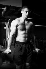 Fototapeta na wymiar Young man training in gym. Black and white photo