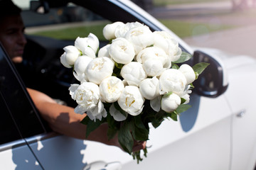 Man in car with bouquet of nice white flowers.