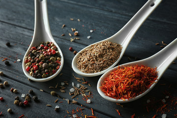 Assortment of spices in ceramic spoons on wooden background