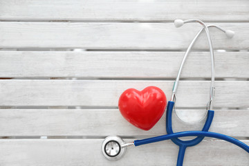 Stethoscope and red heart on wooden table