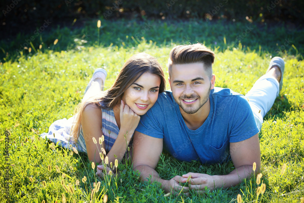 Wall mural Lovely couple lying on green grass