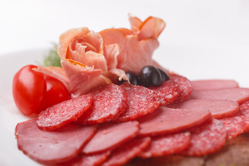 thin slices of sausage and meat on a plate   white background