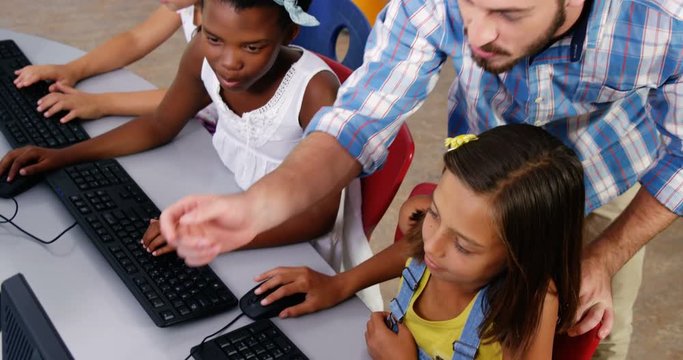 Slow motion of teacher assisting schoolgirls in learning computer at school 4k