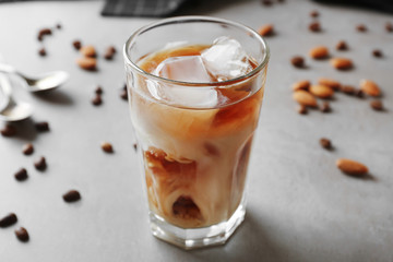 Glass of cold coffee with beans and nuts on table