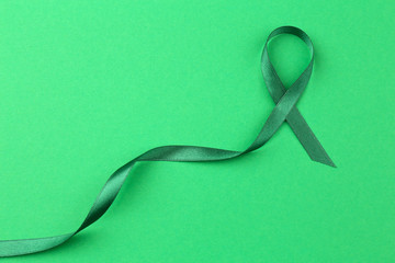 Green ribbon on color background. Mitochondrial diseases and kidney cancer concept