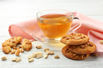 Composition with delicious peanut cookies, nuts and tea on white wooden table