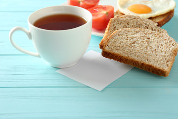 Obraz na płótnie Canvas Cup of tea with tasty breakfast on wooden background